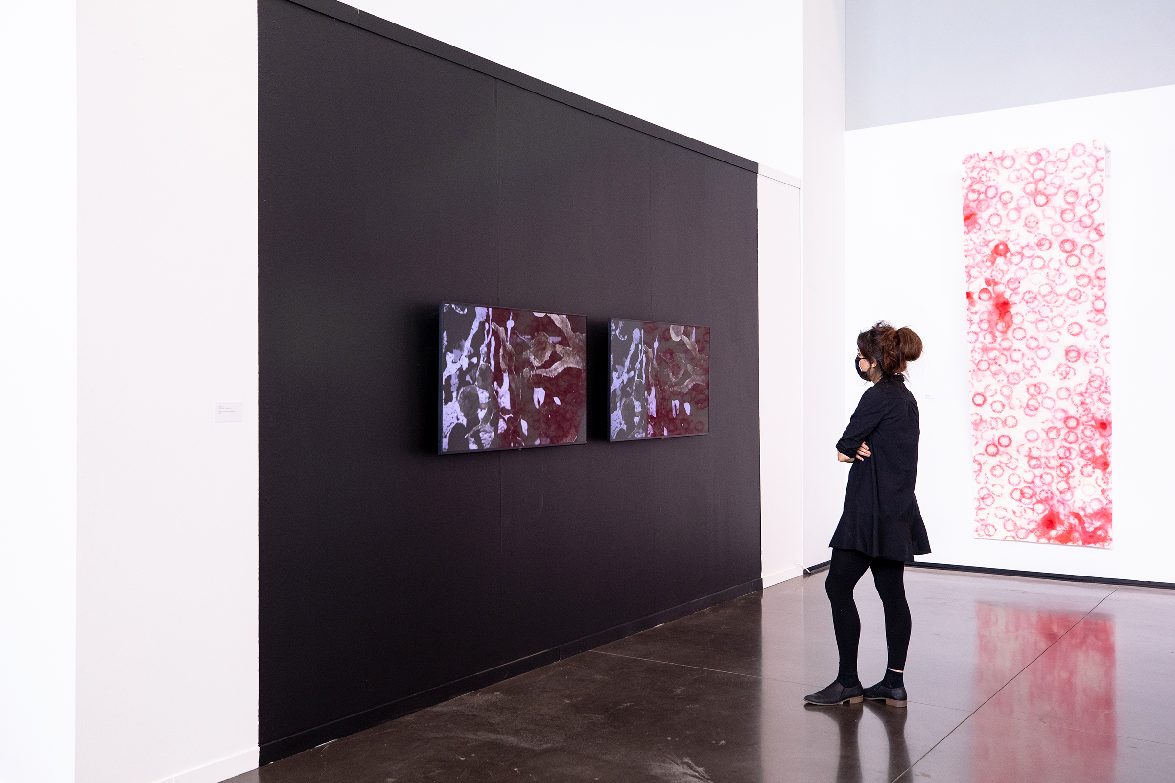 a woman contemplates two prints in a large gallery