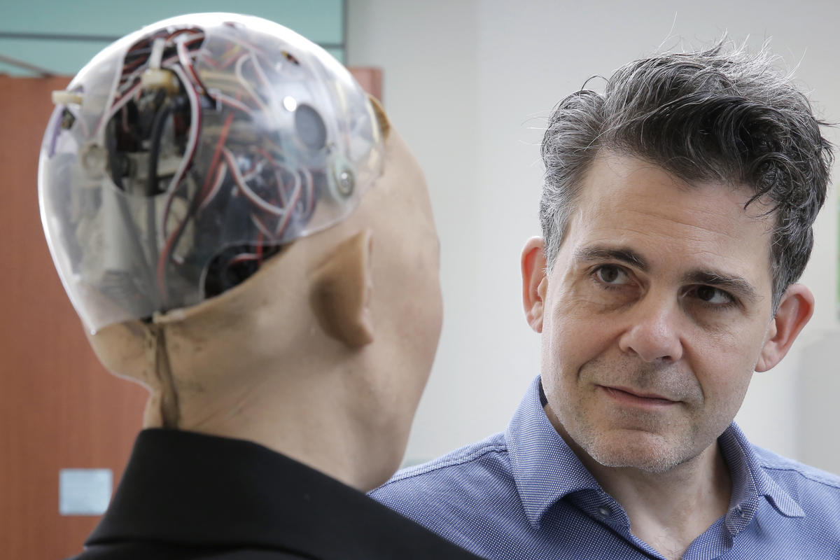 Commencement keynote speaker David Hanson 96 FAV looking at a robot.