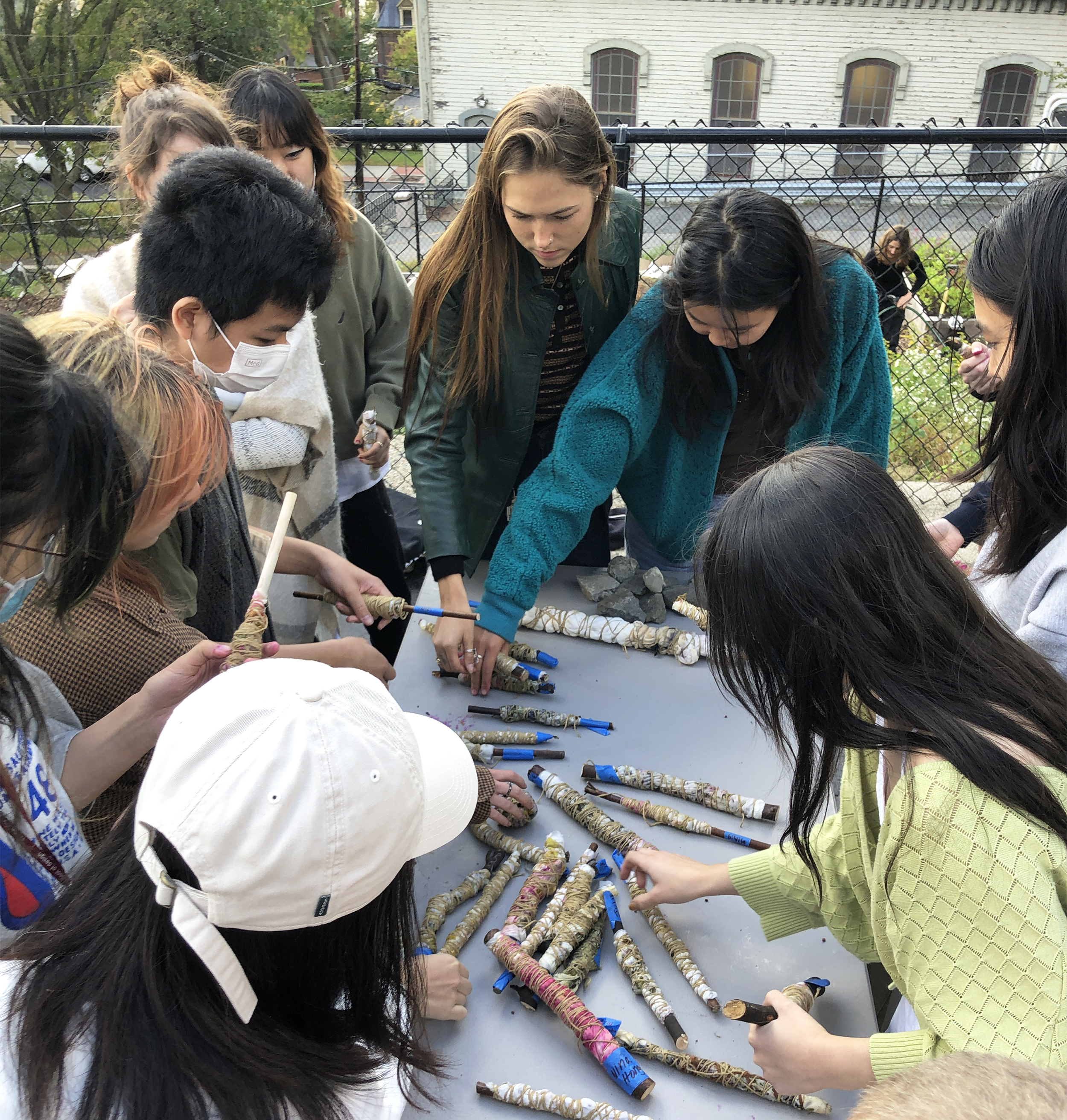 a group of students surrounds a pile of flax 