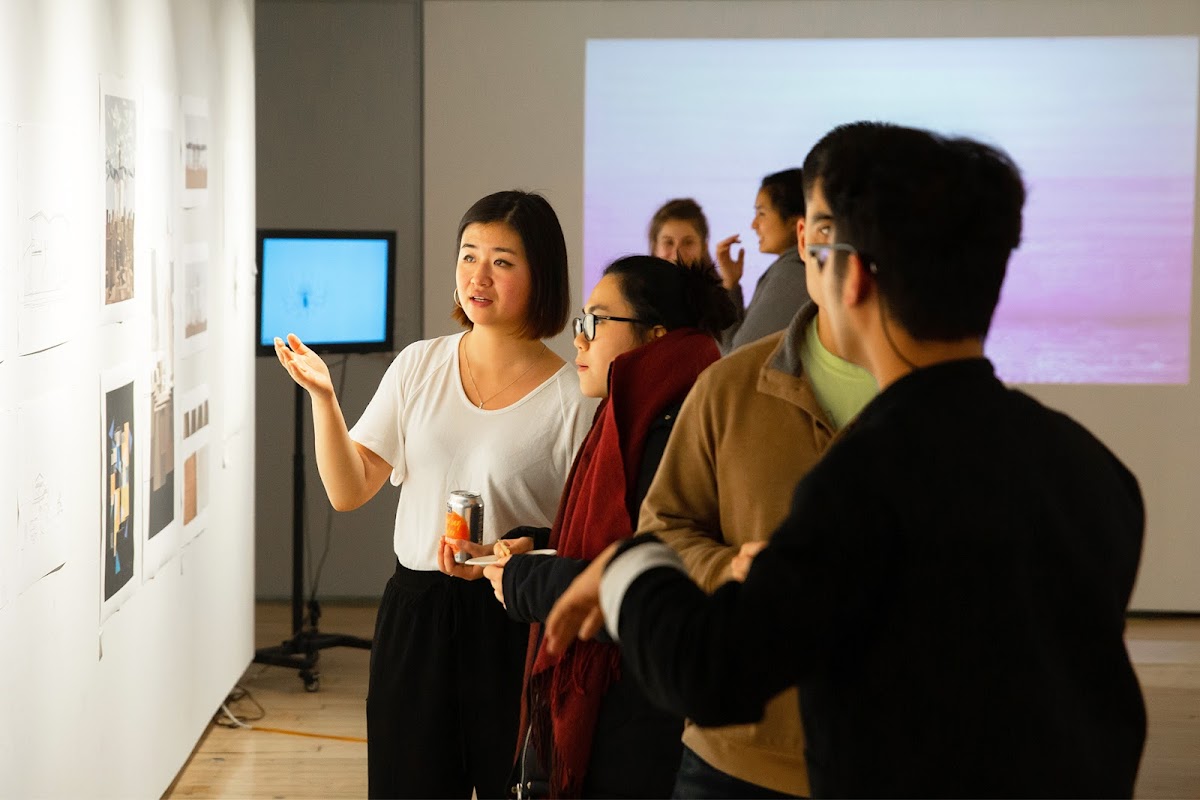 Cherry Yang BArch 20, co-curator of (RE)POSITION, speaking with viewer of the exhibition