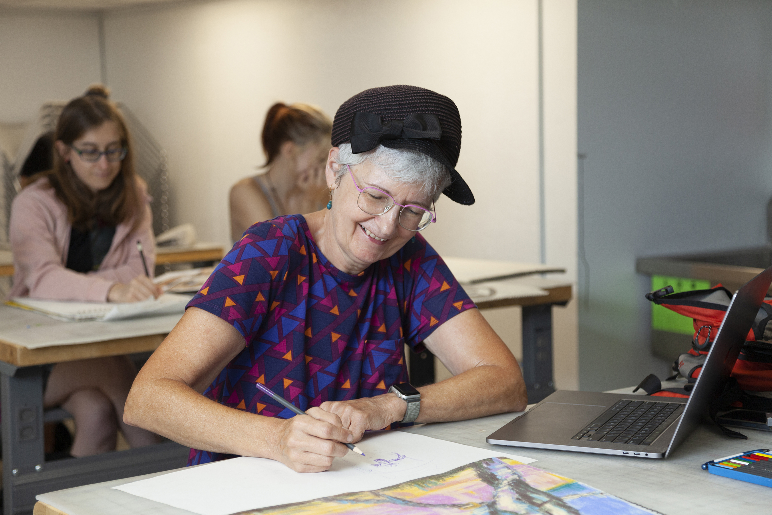 older student drawing at her desk