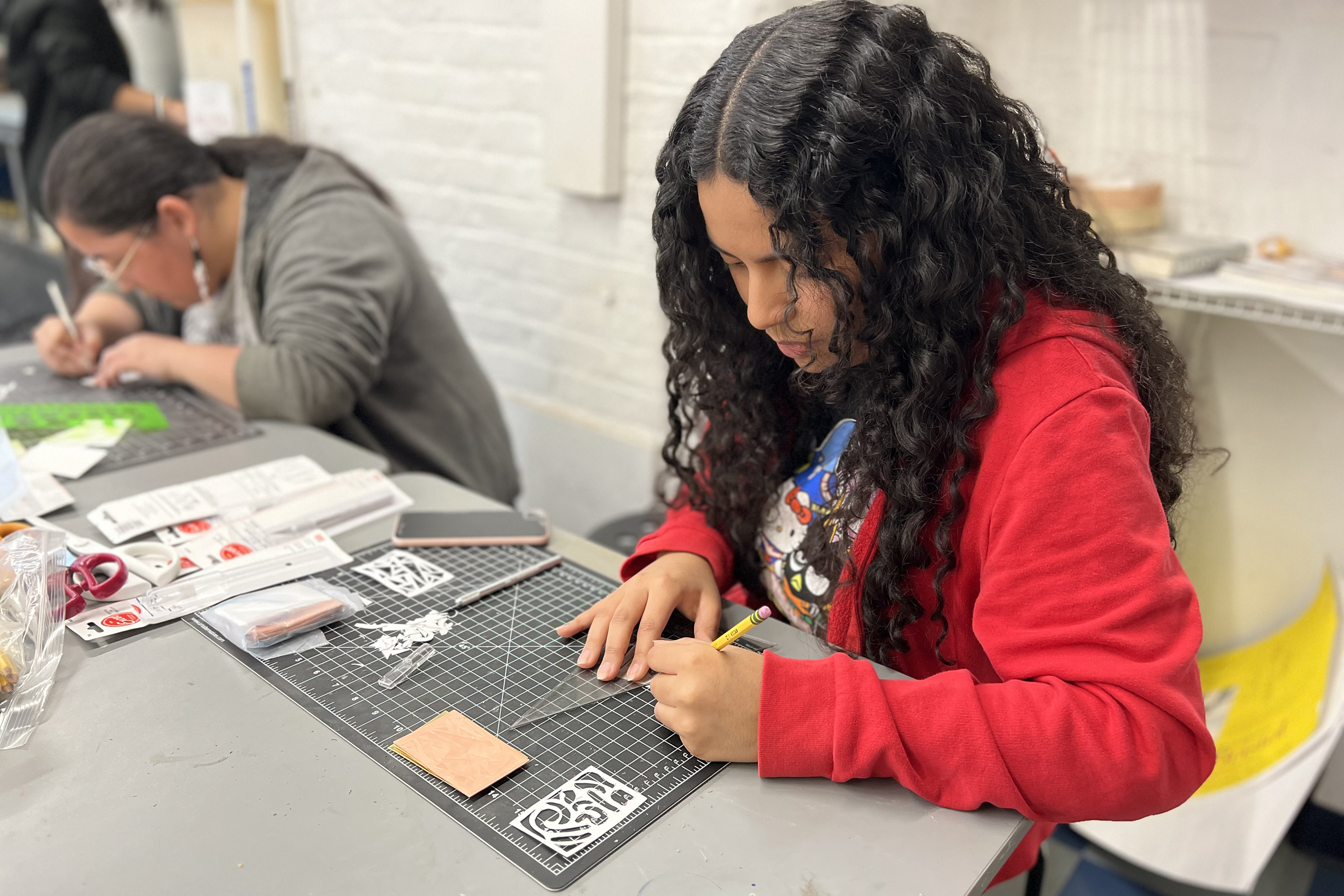 Delci C. cuts out patterns that she will use to texture metals for a custom pin