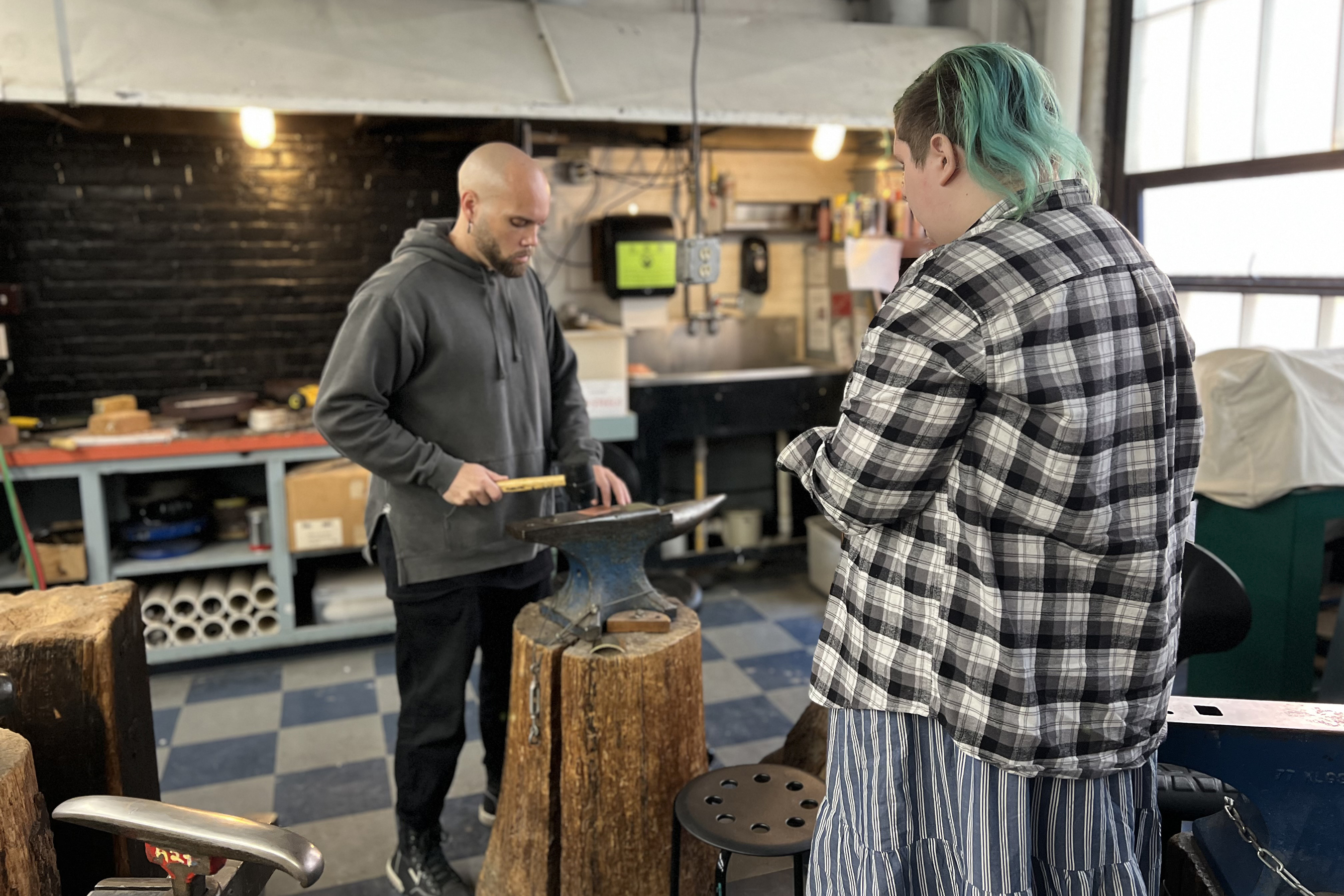Papac shows POD student Sierra E. how to flatten down brass before feeding it into the rolling mill