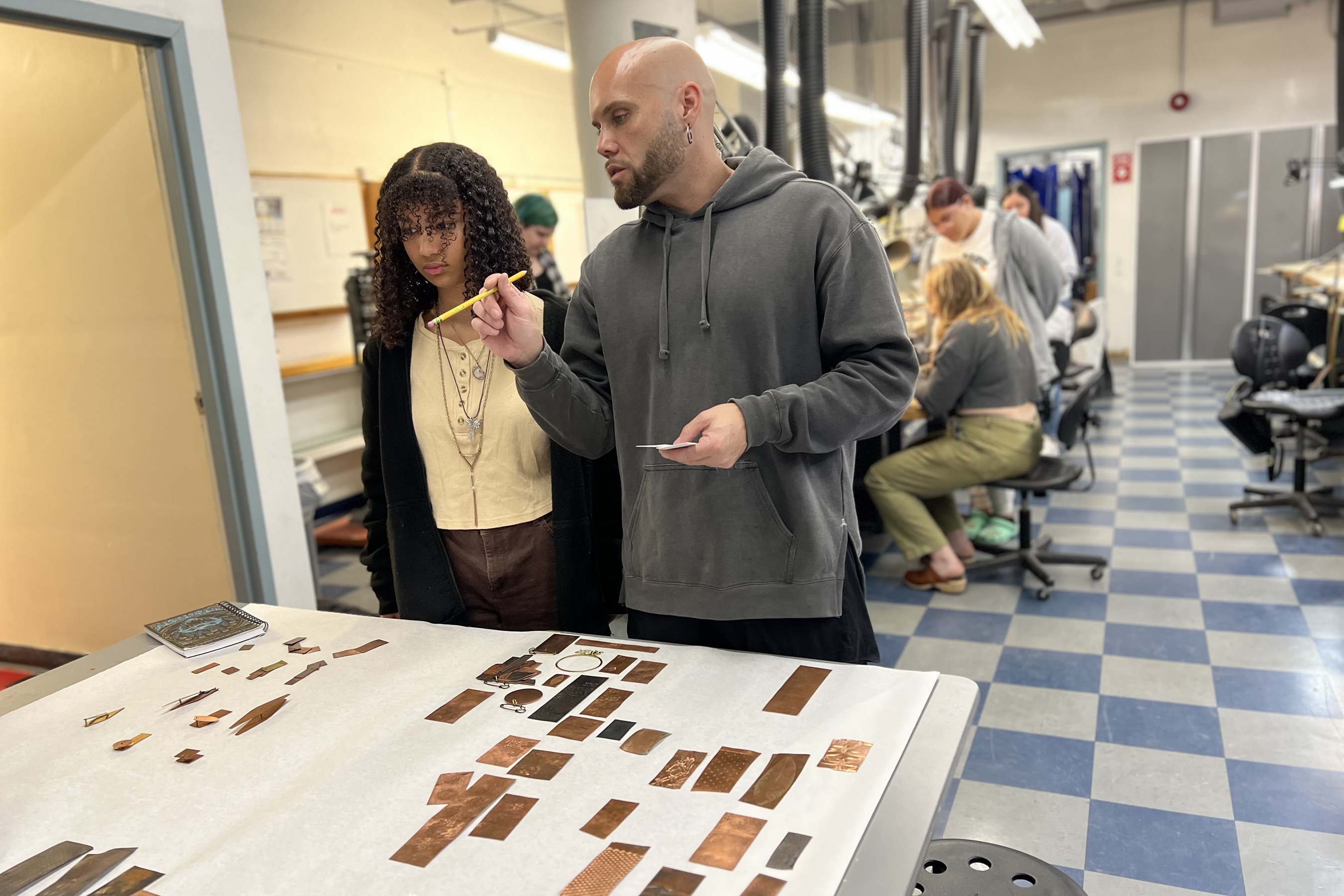 Faculty member Seth Papac shows a student examples of textured metals