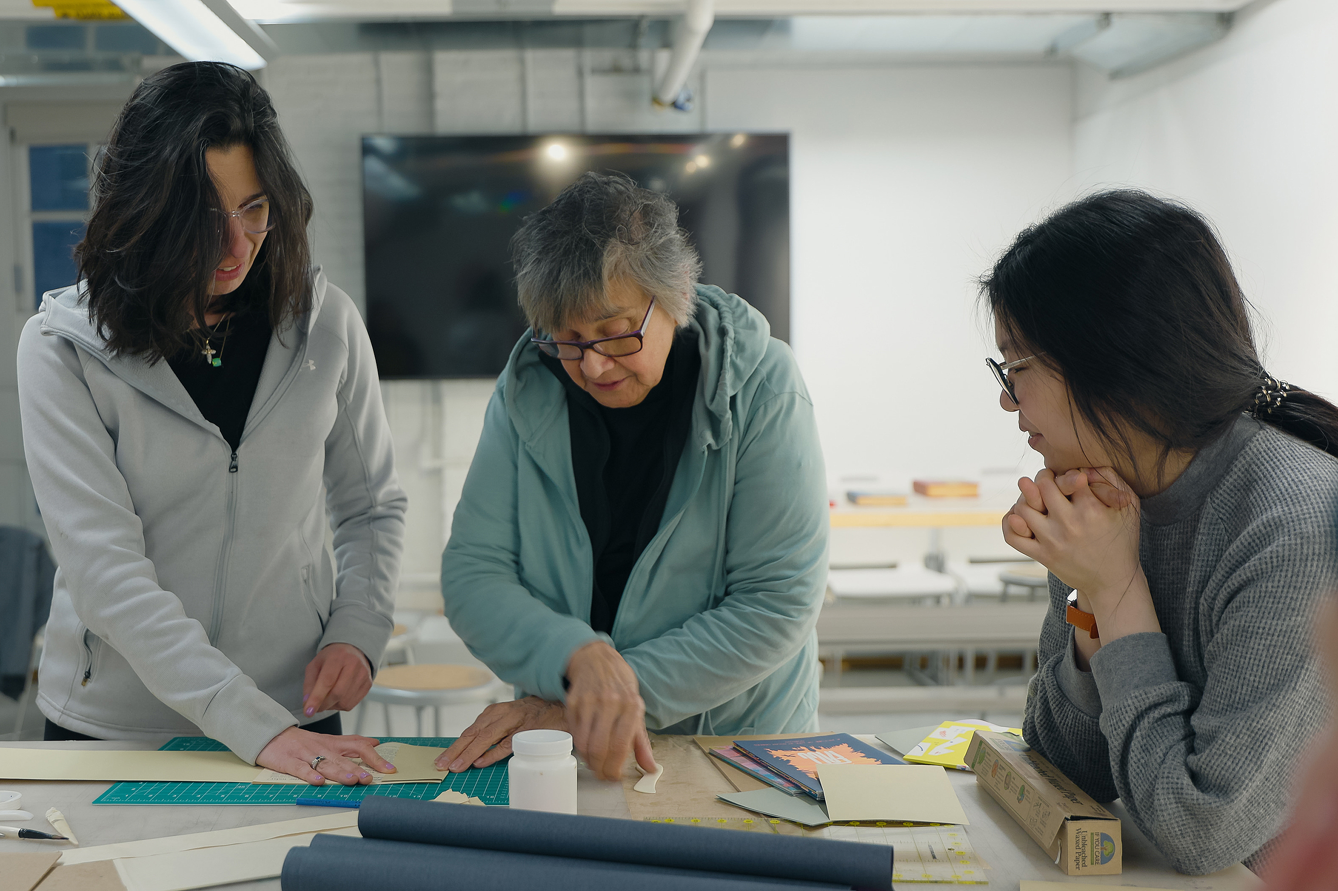 instructor Christine Park oversees work of students in bookbinding CE class