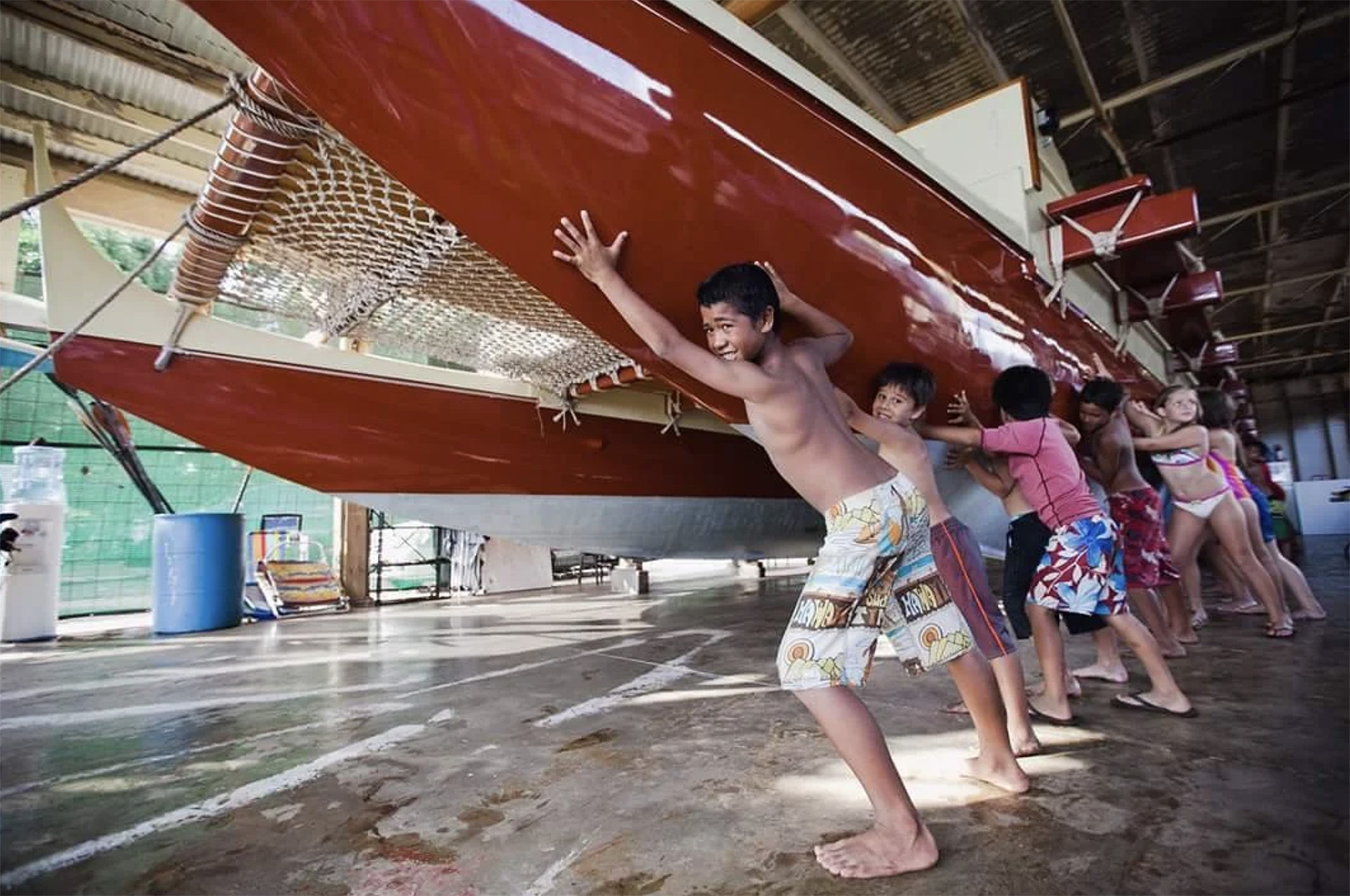 kids in Hawaii work together to lift a traditional craft
