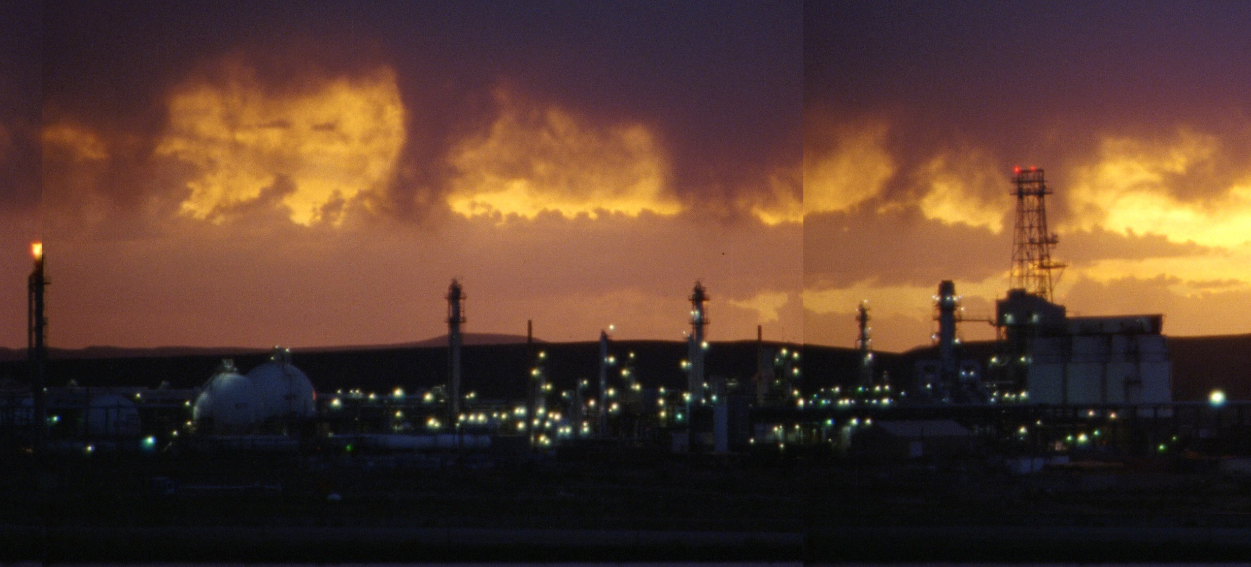 video still of an industrial landscape under dramatic clouds