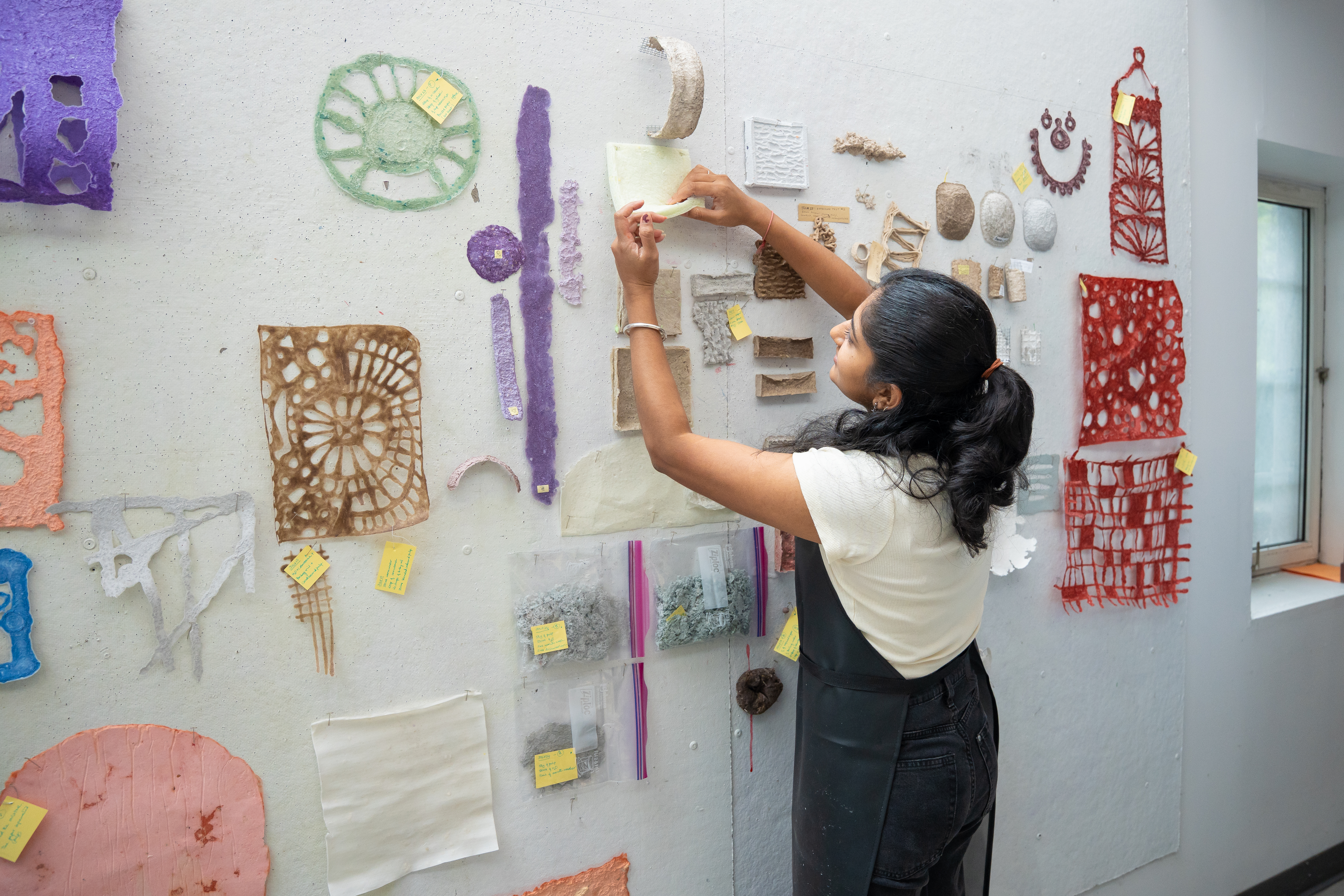 student hangs materials on the wall of the Loop Lab
