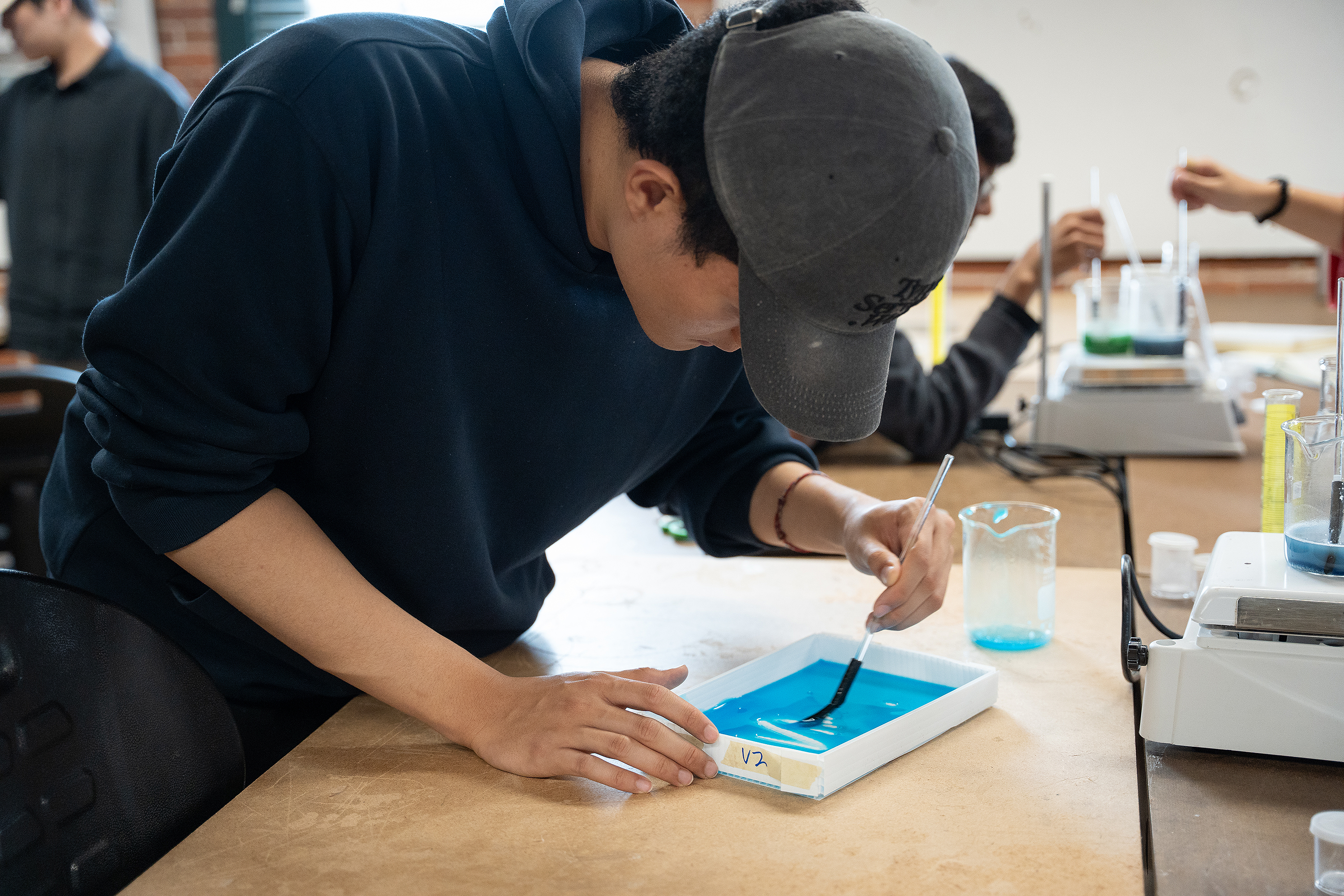 a student mixes a bright blue bioplastic