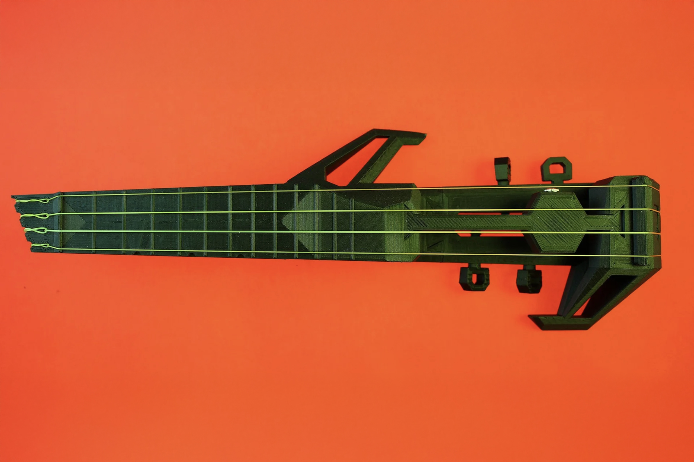 green electric ukulele against bright orange backdrop