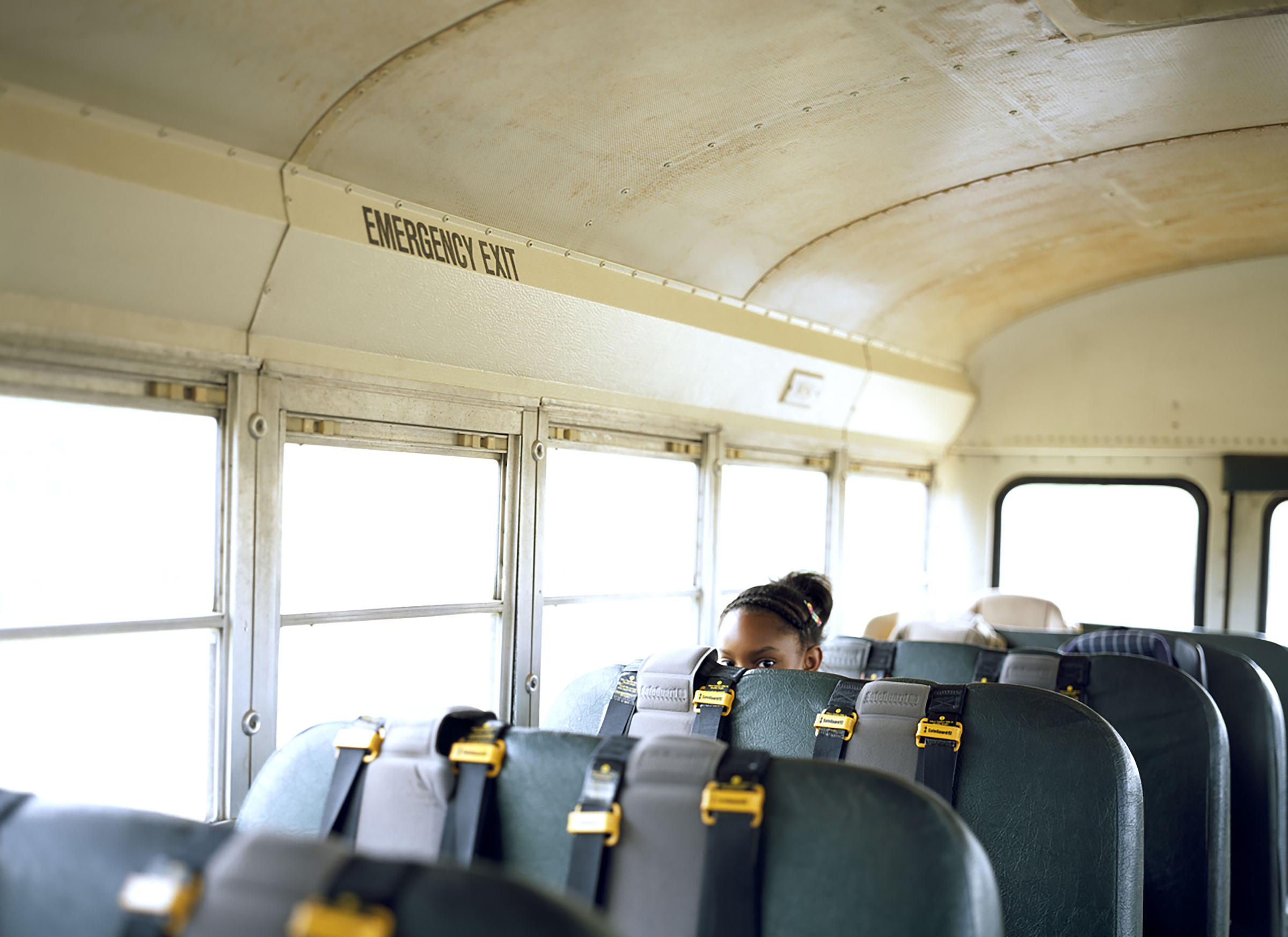 top of the head of a young Black student on an otherwise empty school bus