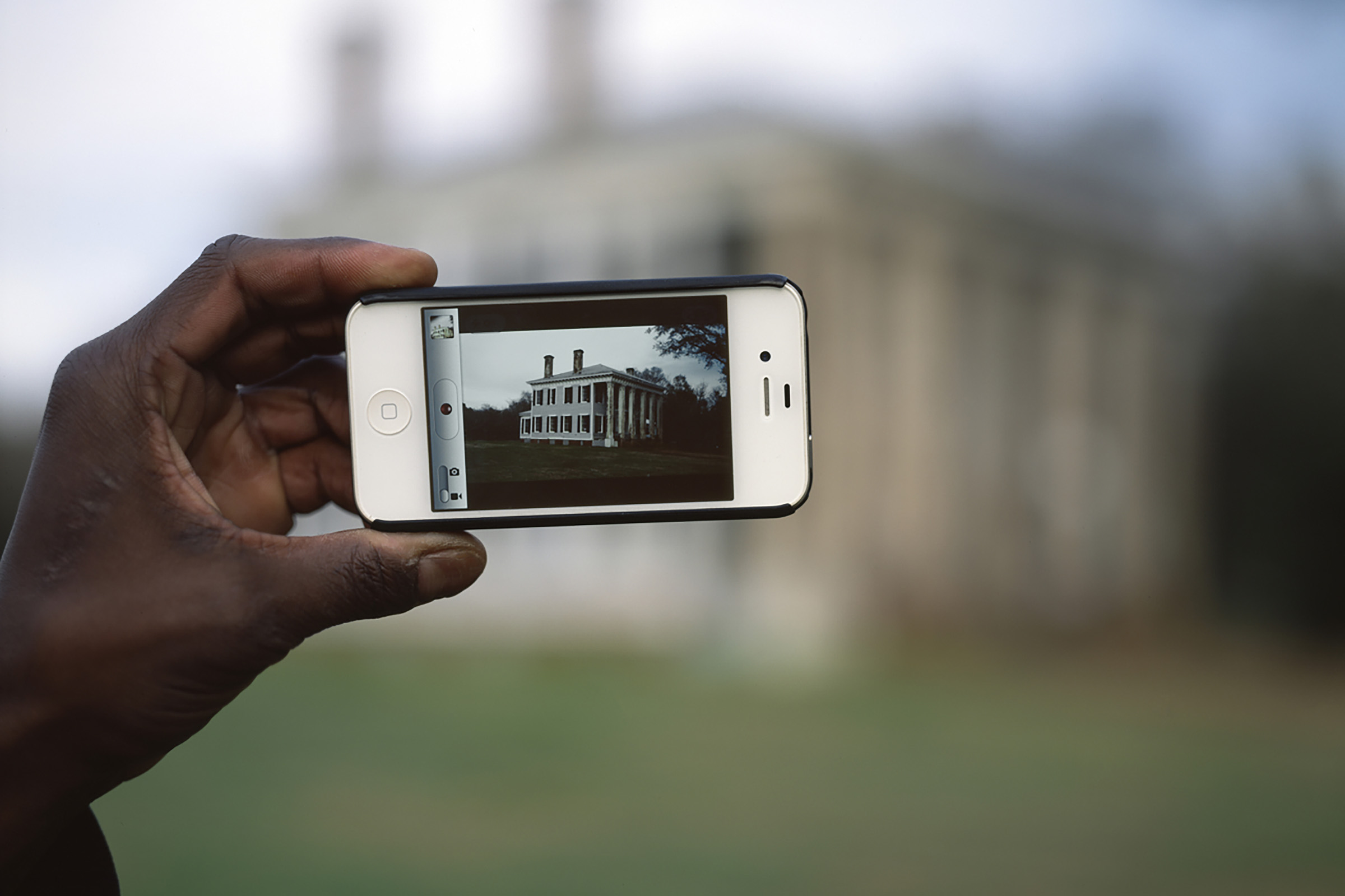 the artist's hand holding up an iPhone while taking a picture of his VA home