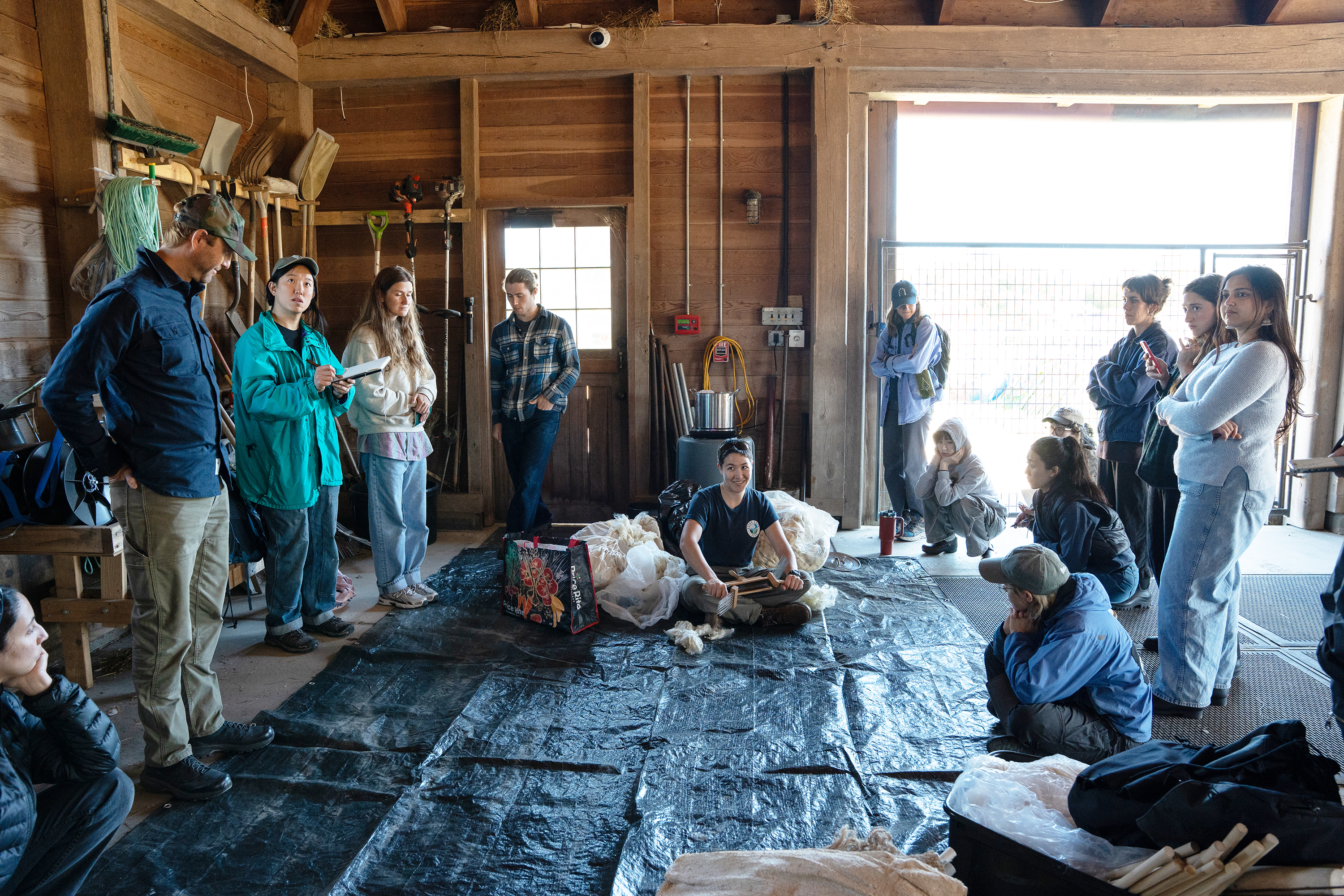 the class circles Clara Boberg as they demo traditional wool-working techniques