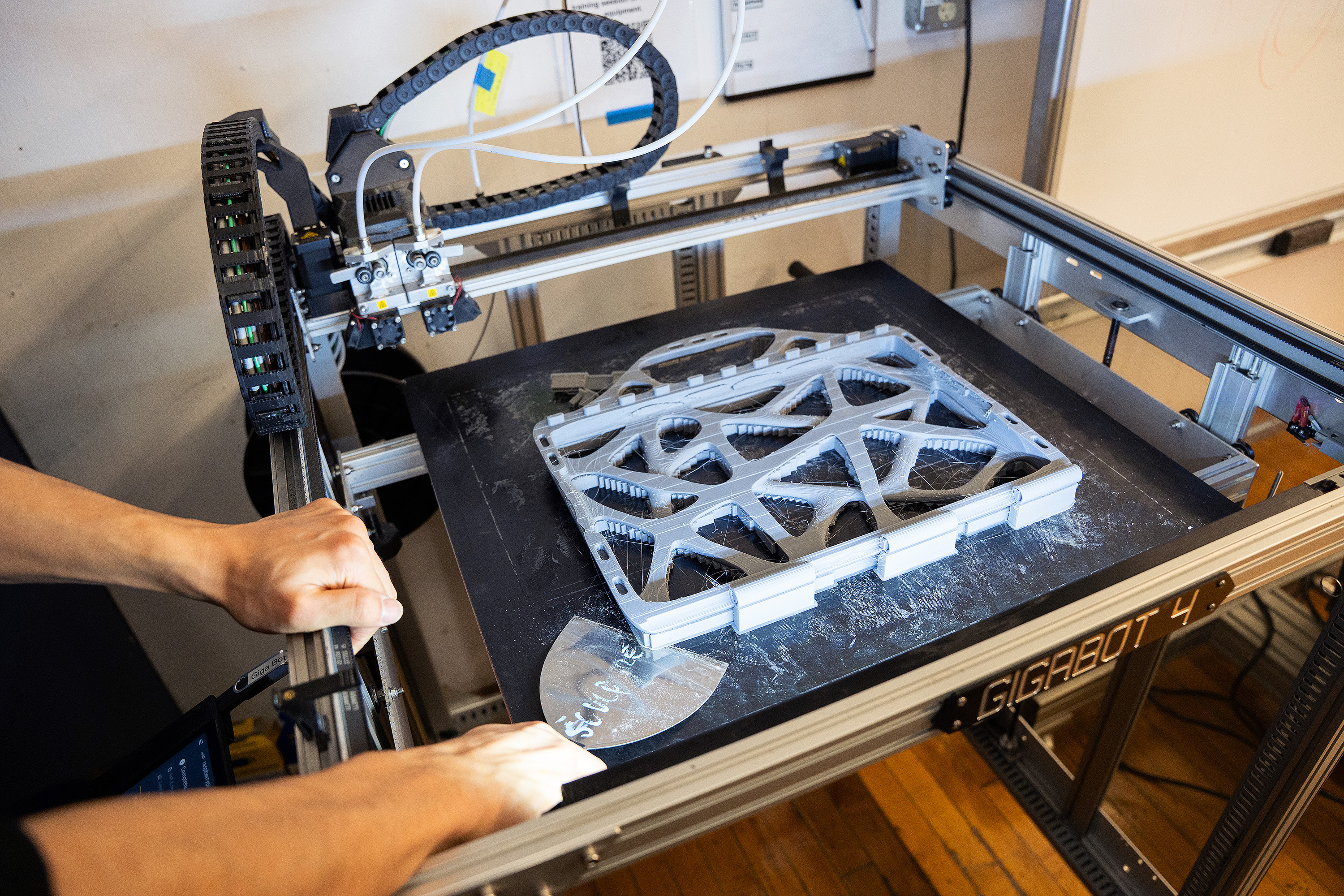 using a putty knife to remove 3D-printed laptop case from machine bed