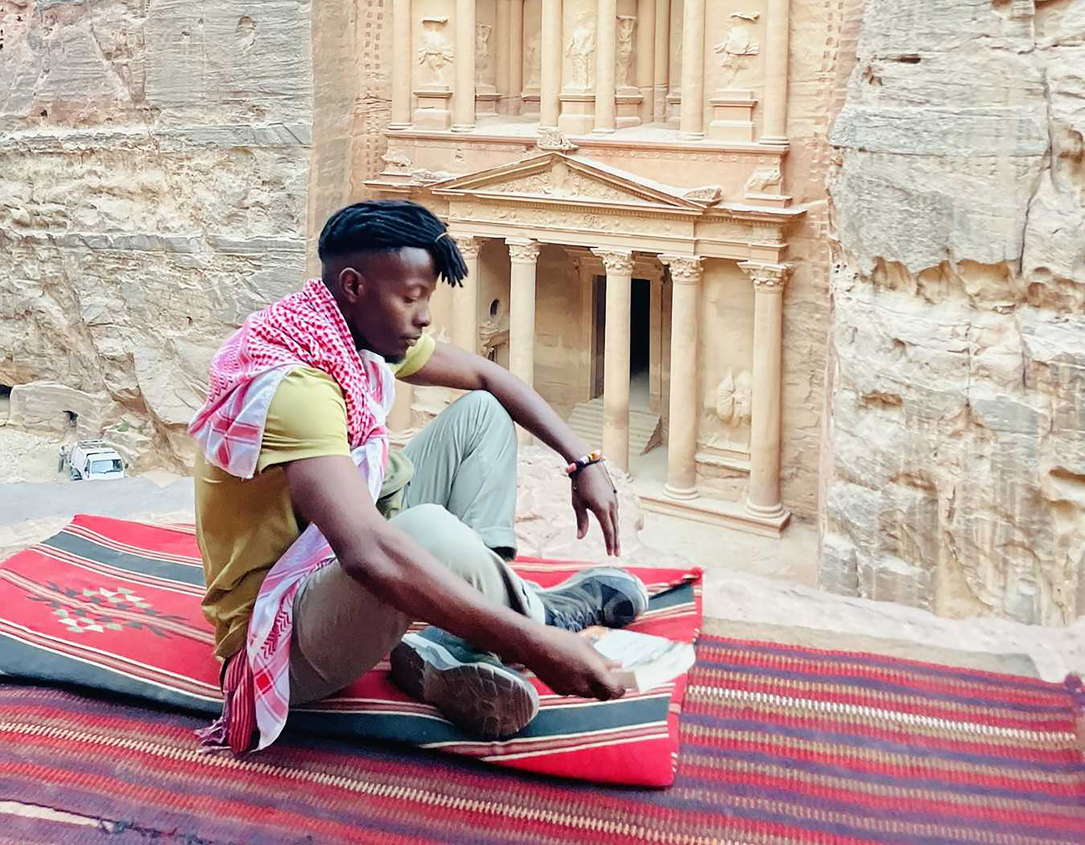 Presidential Fellow Olivier Mbabazi sits cross-legged on a colorful rug