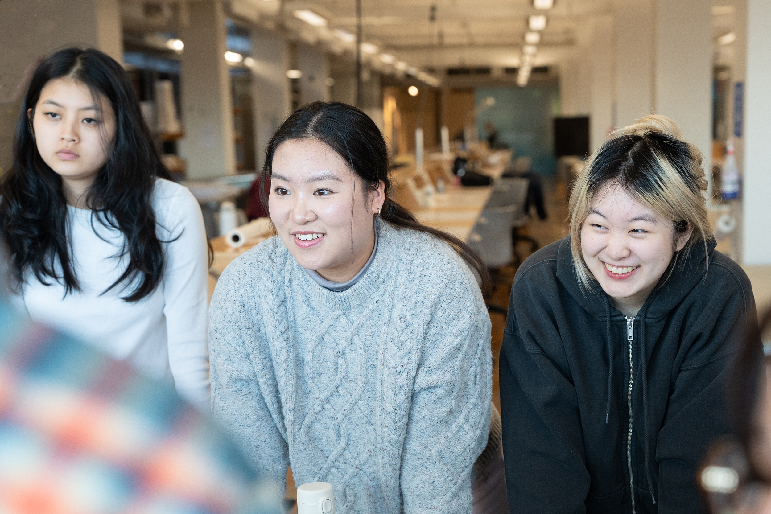 three students discuss exhibition ideas around the table