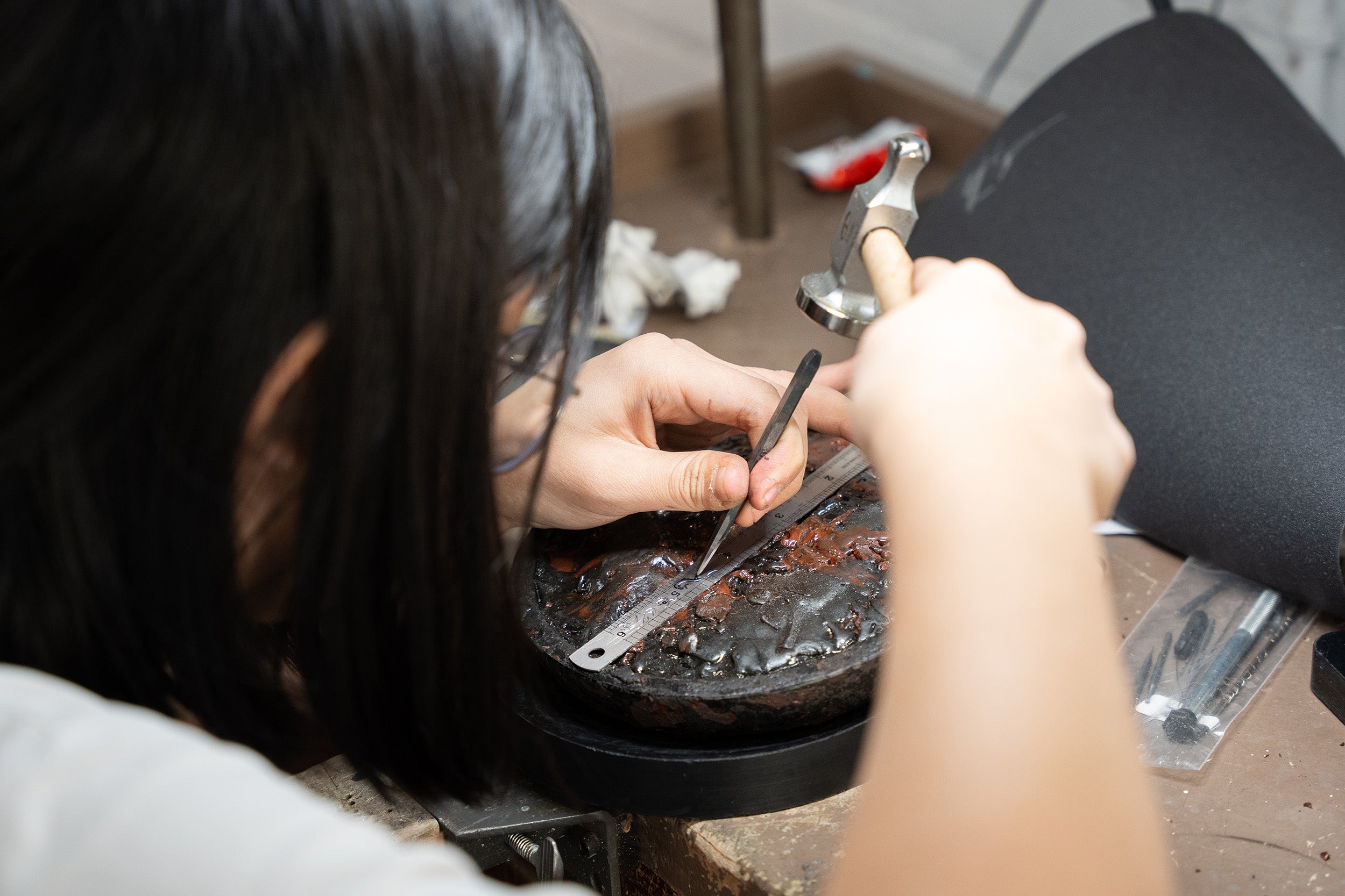 a student at work at her bench with a chisel