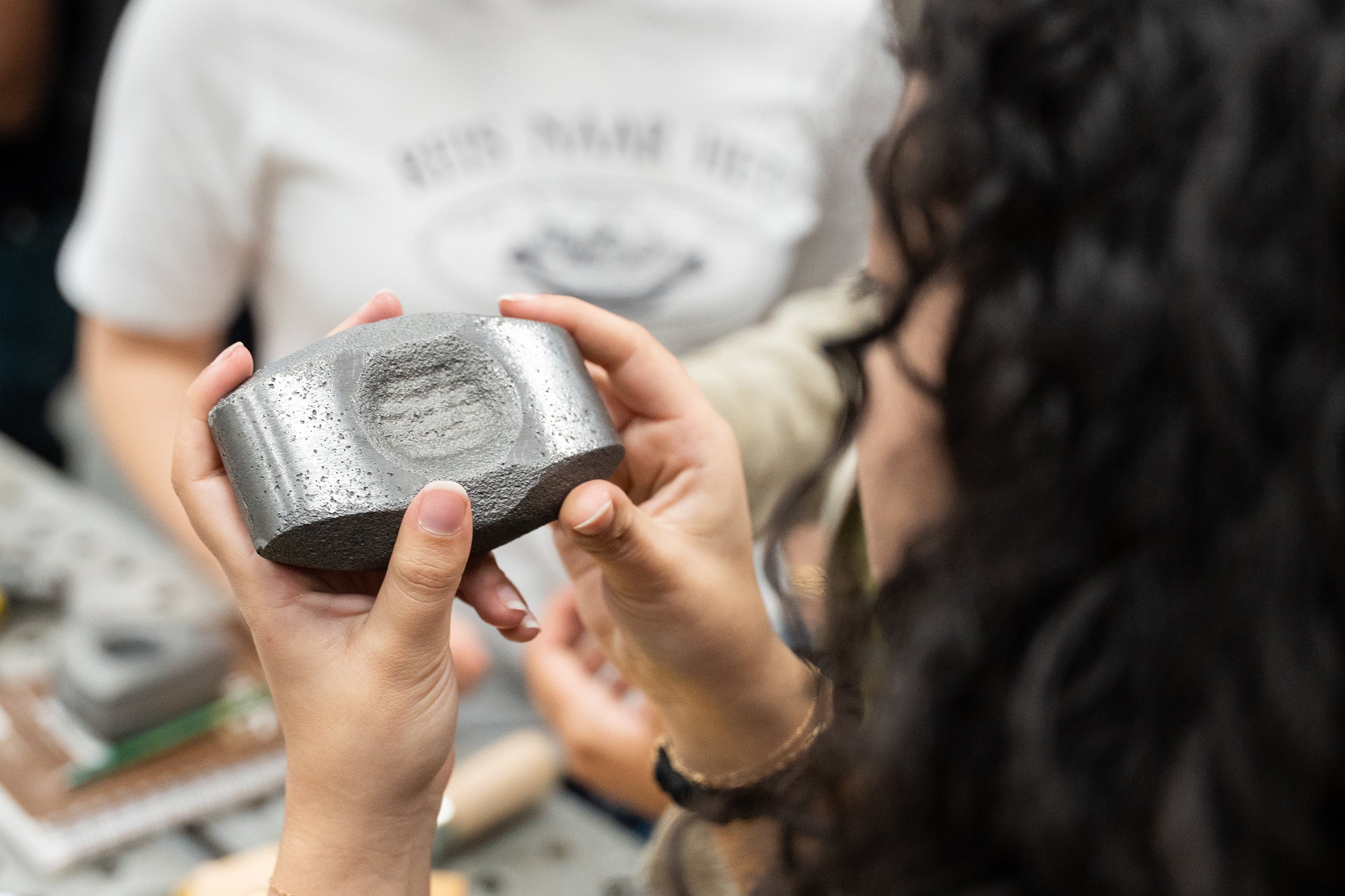a student examines the surface of a cast-iron piece