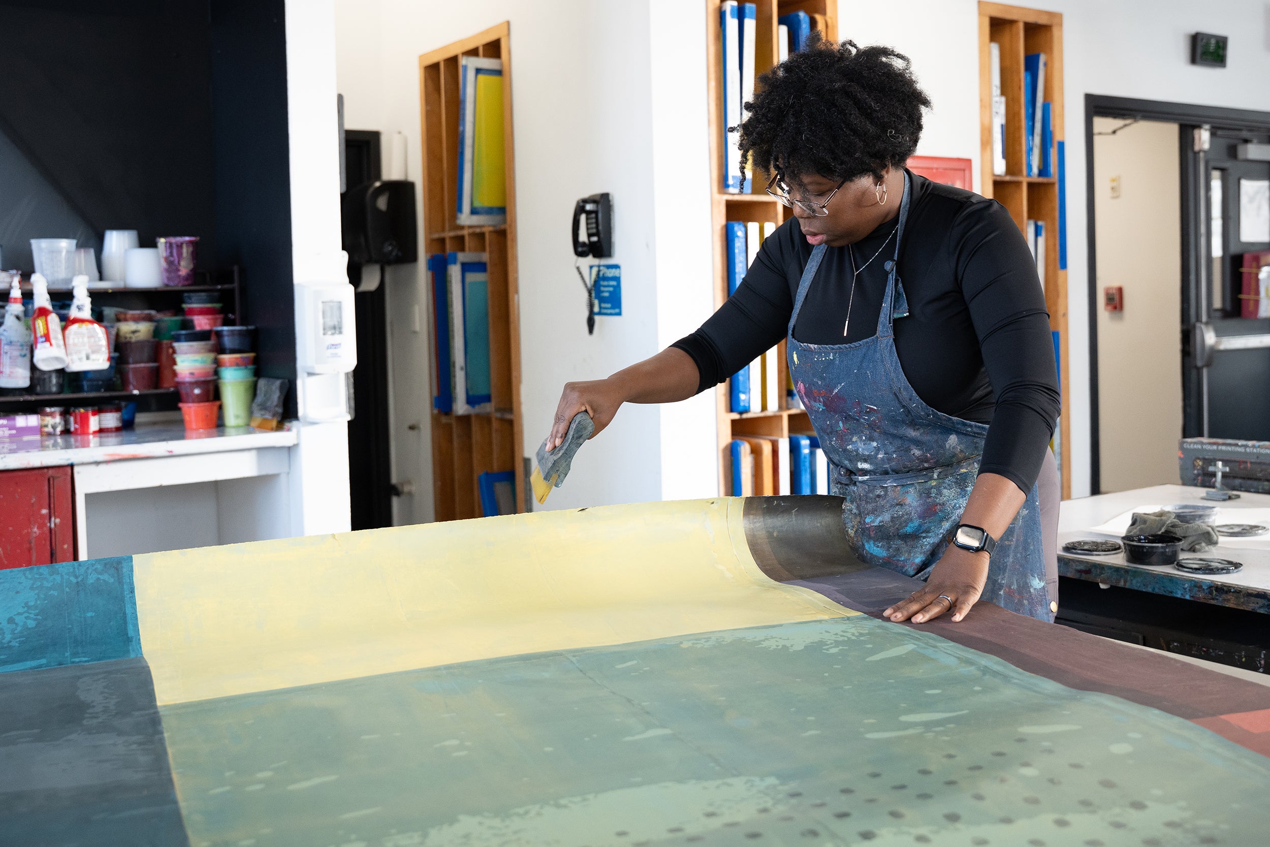 Tyanna Buie applies paint to the background for her print with a small squeegee