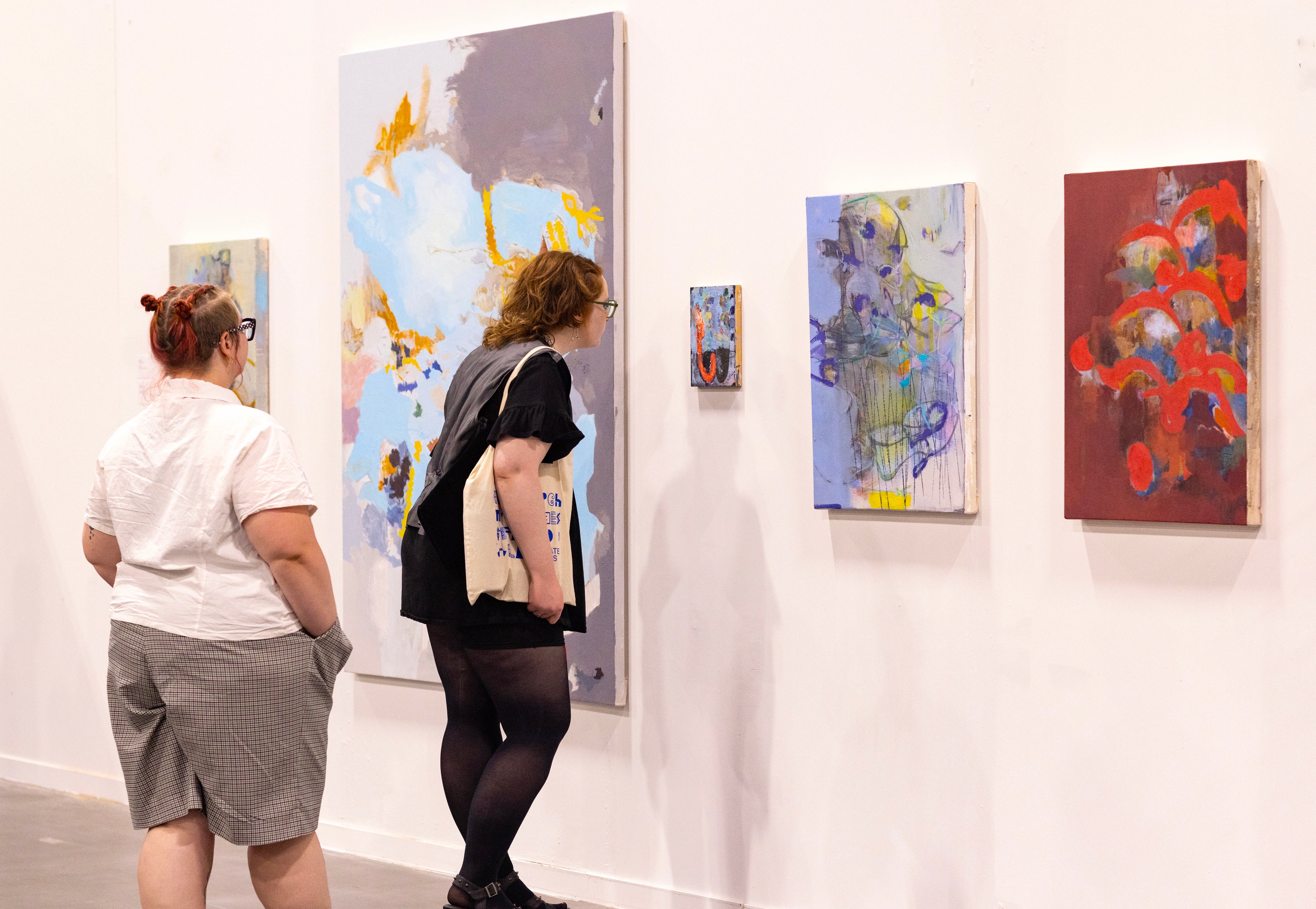 visitors take a close look at a small painting