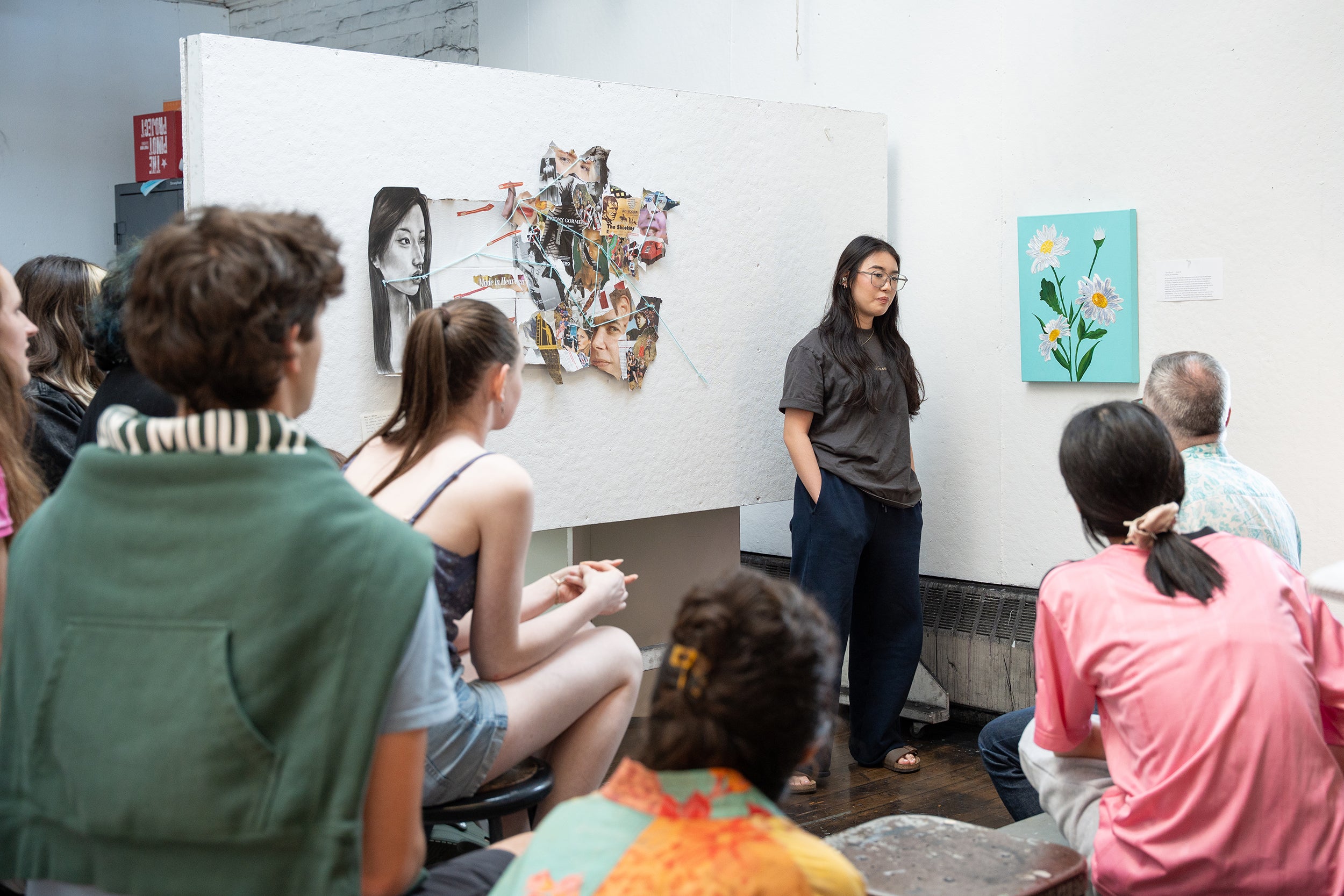a student listens intently to critique about her embroidered painting of daisies