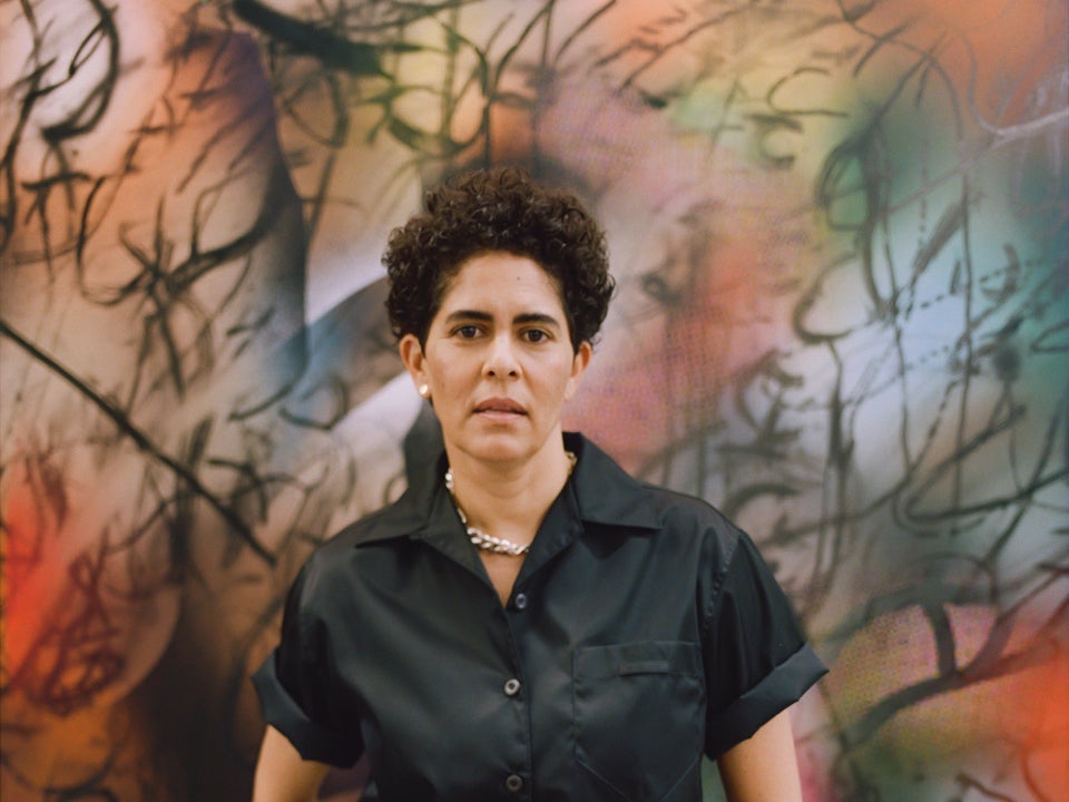 Artist Julie Mehretu stands in front of one of her paintings
