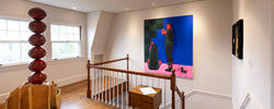 several artworks installed in a home exhibition space near a set of stairs