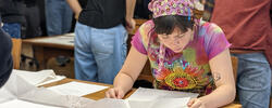 a student examines architectural drawings on large white pieces of paper