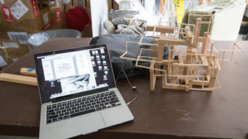 A laptop and wooden object are on a desk.