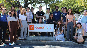 RISD students gathered in a group around a sign reading Y Combinator on a sunny day