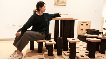 a student sits on one of several multi-level pillars inside a studio space