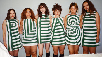 six models stand in a row wearing green and white dresses that spell the word "please"