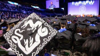 mortaboard decorated with image of dragon and RISD Commencement behind