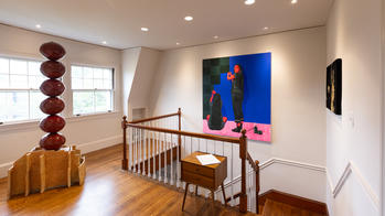 several artworks installed in a home exhibition space near a set of stairs