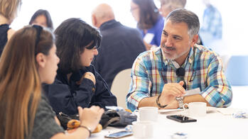 Students and others sitting at a table talking 