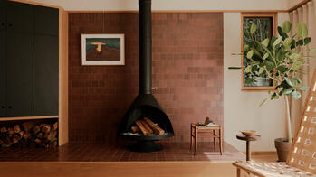 a wood fireplace against a red brick wall at the center of a large living room