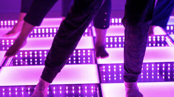 image of people's feet dancing on a lit purple disco stage