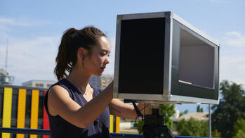 a person peers outdoors through a modified camera atop a tripod mount