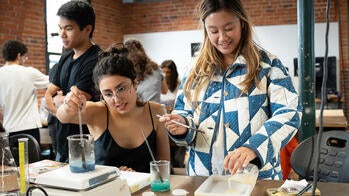 two students conduct biomaterial tests in a brick-walled studio-lab setting