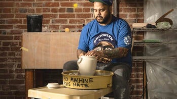 an artist throwing a clay sculpture inside a studio space