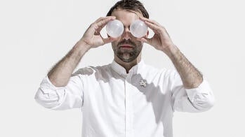 the designer, dressed in white, peers through white binoculars