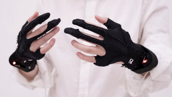 a pair of hands donned in black, glove-like wearable technology