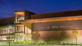 a college building, with a sign reading LIBERAL ARTS BUILDING on its outer face, sits below a navy blue night sky