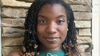 Nadia Meadows MFA 28 SC in a teal shirt in front of a stone wall