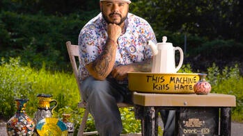 artist Roberto Lugo with a pottery wheel that says "this machine kills hate"