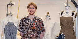 Hawk poses with works in progress on dress forms