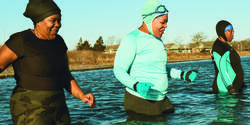 three Black women wade into the sea