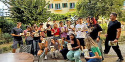 a group of students holds their paintings ourside in italy