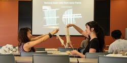 two students hold up small looms