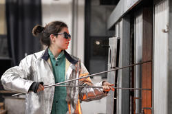 a student working on a piece for the exhibit in RISD's hot shop